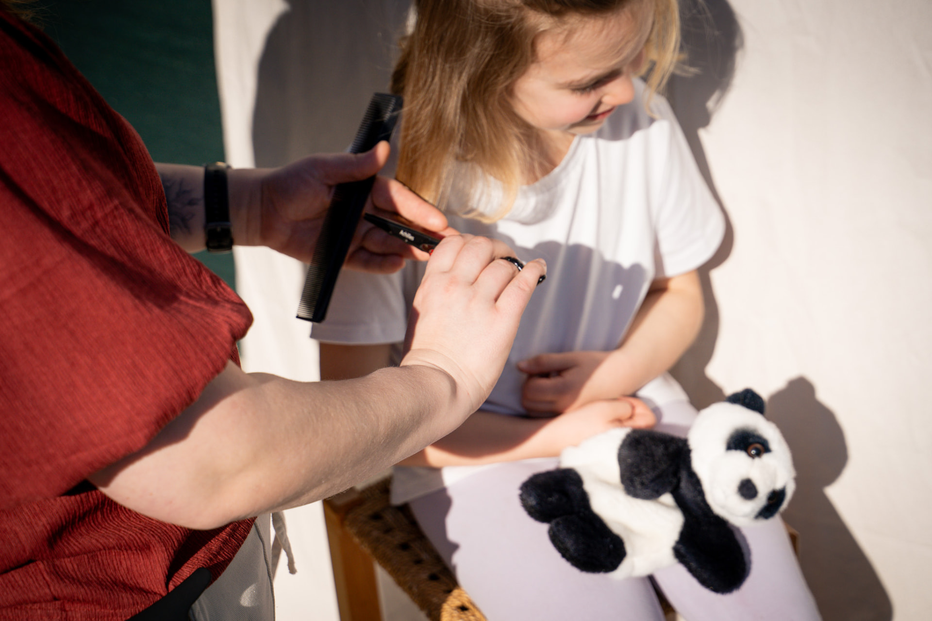 Kinderkapsel — meisje met pandaknuffel tijdens de knipbeurt